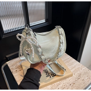 Detail of light green ruched handbag with pearl bow, heart charm and silver chain