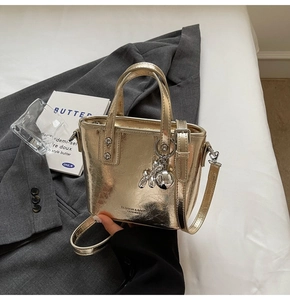 Detailed view of the gold bucket bag featuring a balloon dog charm on a blazer