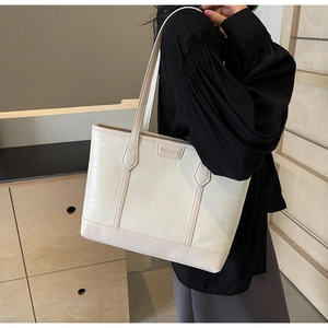 Detailed view of crocodile pattern texture and metal logo on the cream white tote bag
