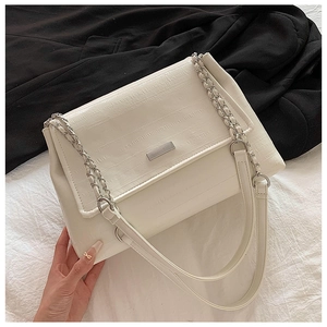 Detail of off-white crocodile embossed texture and silver chain strap on a tote bag