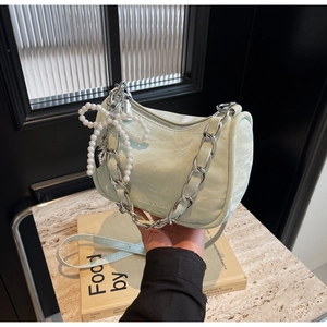 Close-up of mint green handbag featuring pleated texture and pearl bow charm