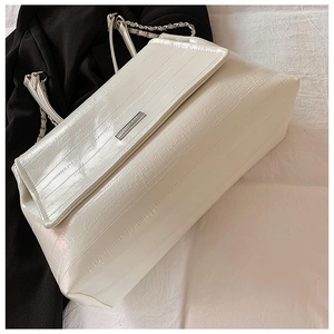 Detail of white crocodile texture leather and silver chain strap on a shoulder bag