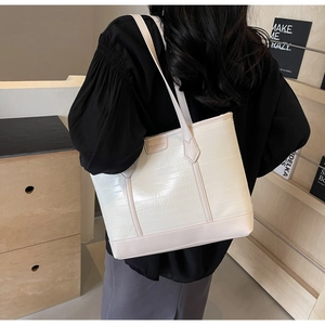 Detail of cream tote bag featuring embossed crocodile pattern and Meiduola brand tag