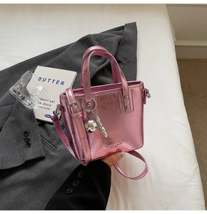 Detail of metallic pink mini bucket bag with silver ball charm on grey blazer