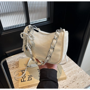 Detail of cream-white pleated handbag with chunky metal chain and pearl heart charm