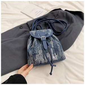 Détail du mini sac à dos en denim avec paillettes argentées et finitions en cuir bleu