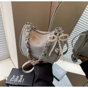 Detail of grey pleated crescent bag with pearl bow charm and silver chain strap