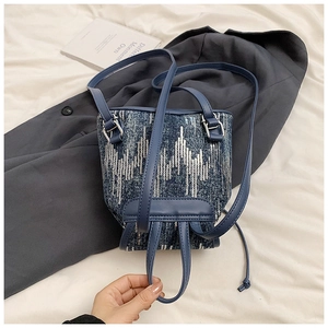Détail d'un mini sac à dos en denim avec paillettes argentées et sangle bleue réglable