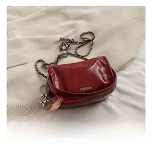 Detail of burgundy glossy leather bag with silver chain and metal balloon dog charm