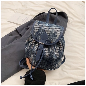 Détail d'un mini sac à dos en jean à paillettes bleu foncé avec boucle et cordon de serrage