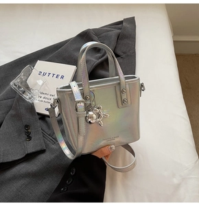 Close-up of silver iridescent bucket bag with fashion logo and balloon dog charm