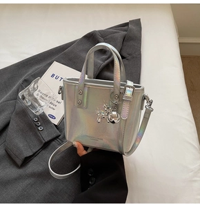 Detail of silver holographic bucket bag with balloon dog charm and removable strap