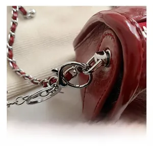 Close-up of premium silver metal chain and polished red patent leather on lady crossbody bag