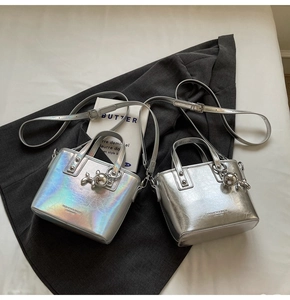 Detail of silver holographic bucket bags with metal balloon dog charms and straps