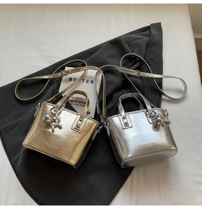 Detail view of stylish metallic silver and gold mini bucket bags with bear pendants