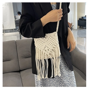 Detail of a handmade cream macrame crossbody bag with long tassels on a fashion model