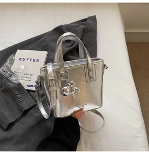 Detail of silver metallic tote bag with adjustable strap and metal rabbit charm