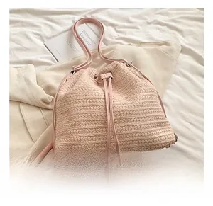 Detail of light pink woven straw bucket bag with leather drawstring and textured finish