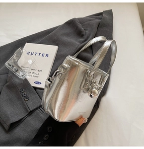 Detailed view of silver mirror bucket bag with metallic ball charm and thin strap