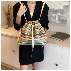 Detail of colorful striped straw backpack with drawstring closure and slim white straps