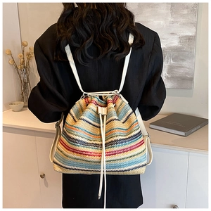 Detail of colorful striped woven straw backpack with drawstring closure and white straps