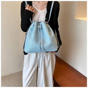 Detail of light blue straw backpack with fine woven texture and drawstring closure