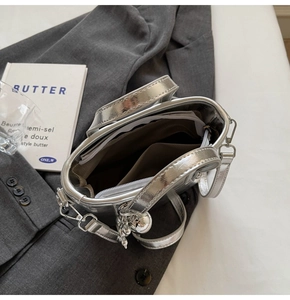 Detail view of the silver bucket bag interior with zipper pocket and metal ball charm