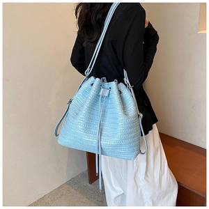 Detailed view of light blue woven bucket bag with drawstring closure and metal hardware