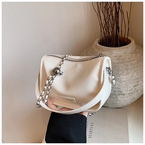 Detailed view of cream leather pillow bag with woven chain strap and metal ball buckle