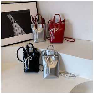 Détail de mini sacs à main brillants avec nœuds en perles et texture lisse métallique