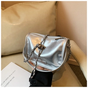 Close-up of silver pleated faux leather bag with metallic chain and spherical charm