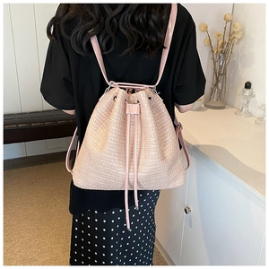 Rear view of a stylish pink straw bucket backpack with leather drawstrings and thin straps