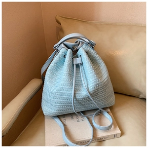 Detailed close-up of light blue knit bucket bag with woven texture and drawstring closure