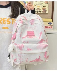 Detail eines weißen Canvas-Rucksacks mit rosa Landschaftsdruck und Plüsch-Anhänger