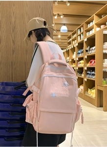 Pink school backpack detail featuring star embroidery and braided side charm ornament