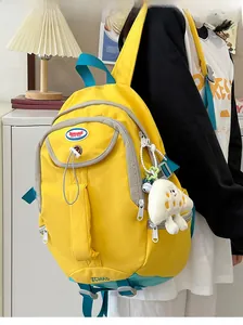 Detail of yellow nylon backpack featuring teal straps and a cute white cloud charm