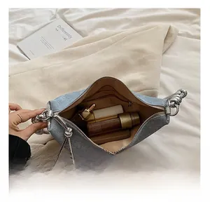 Macro view of denim texture handbag interior with spacious capacity and silver woven handle