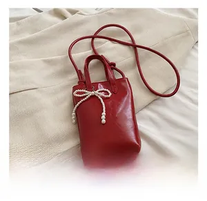 Détail du sac seau rouge avec décoration de perles blanches et fini brillant
