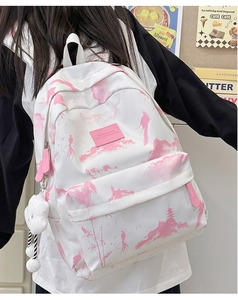 Nahaufnahme eines weiß-rosa bedruckten Rucksacks mit süßem Plüschbär-Anhänger für Damen