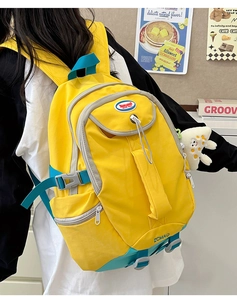 Side view of a bright yellow nylon backpack with deep teal straps and a plush star charm
