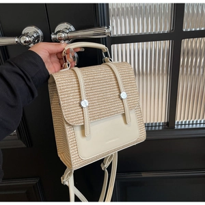 Detail of straw and cream leather backpack showing top handle and buckle straps