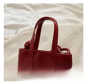 Détail du sac à main rouge en cuir verni brillant avec design à nœud latéral
