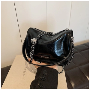 Detail of glossy black handbag with silver chain strap and decorative metallic sphere