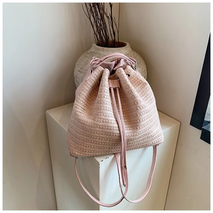 Detail of pink straw bucket bag featuring woven texture and leather drawstring closure