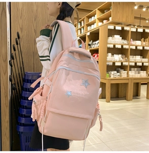 Pink student backpack with star embroidery and functional zipper detail shown on model