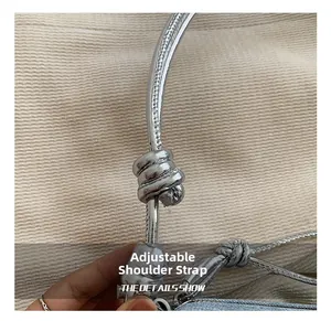 Detail of adjustable silver metallic shoulder strap with knot and grainy texture