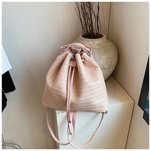 Detail of light pink woven straw backpack featuring leather drawstring and silver hardware
