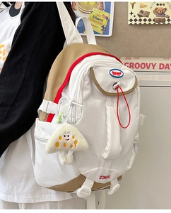 Side view of beige nylon backpack with red drawstrings and a mushroom plush charm detail