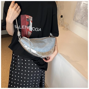 Detail view of denim and metallic silver fabric patchwork on a crescent shoulder bag