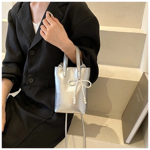 Détail d'un mini sac argenté avec nœud en perles sur un escalier minimaliste